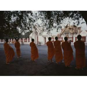  Buddhist Monks in Orange Robes Stand Outside an Ornate 